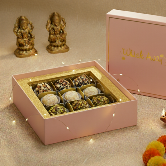 Pink box of assorted chocolates with decorative items on a beige surface